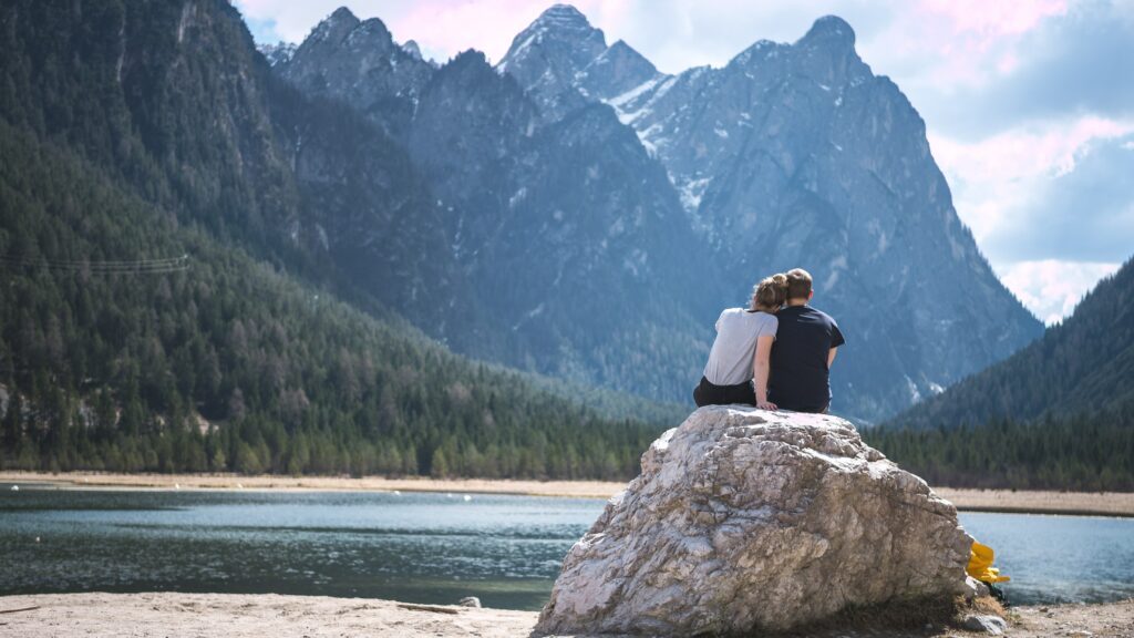 Two people sitting on a rock in picturesque landscape