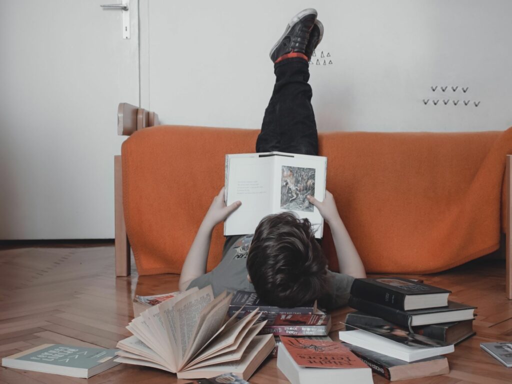 Young boy laying on the floor reading a book